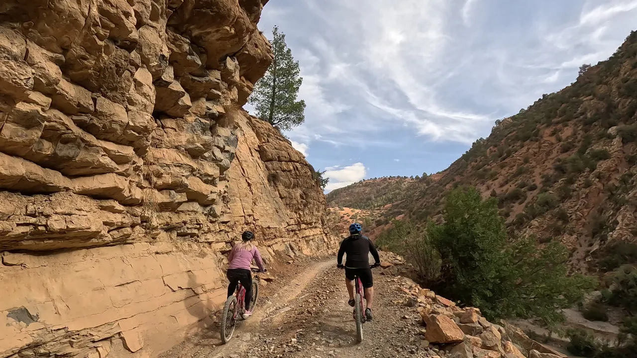 Riders on e-bikes climbing a valley road in the High Atlas